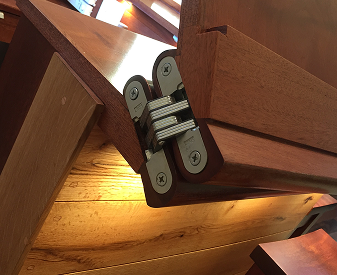 Close-up of a SOSS invisible hinge installed on a wood door panel for concealed hardware design.