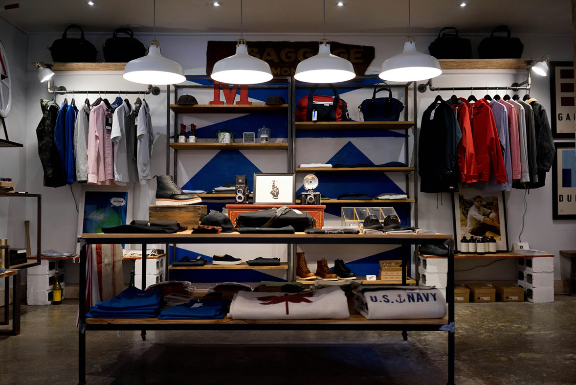 Modern retail clothing display with shelving, hanging apparel and overhead lighting.