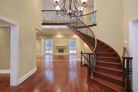 Open home foyer with curved staircase, hardwood floors and balcony railing.