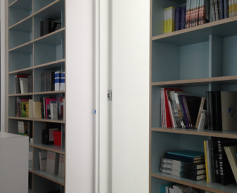 Hidden bookcase door with concealed hinge hardware in a modern shelving wall.