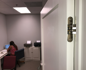 SOSS invisible hinge installed on a white office door near a workspace.