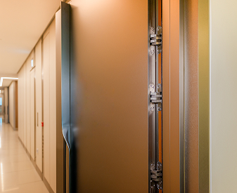 SOSS invisible hinge installed on a partially open commercial hallway door.