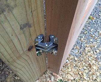 SOSS invisible hinge installed on an outdoor wood gate post.