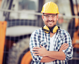 Construction worker wearing a hard hat and hearing protection at a job site.