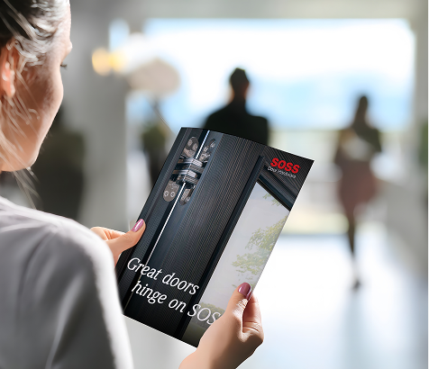 Person holding a SOSS invisible hinge brochure in a modern interior.