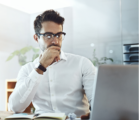Professional reviewing work on a laptop in a modern office setting.