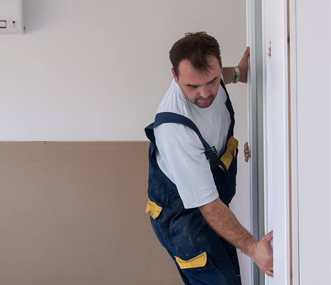 Contractor installing a white interior door in a residential space.