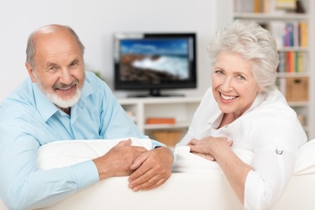 Couple looking over back of couch with TV in background