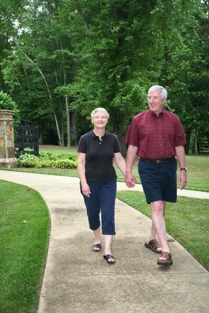 Retired couple walking along sidewalk in park