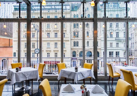 modern seating and table settings in European restaurant overlooking tall buildings